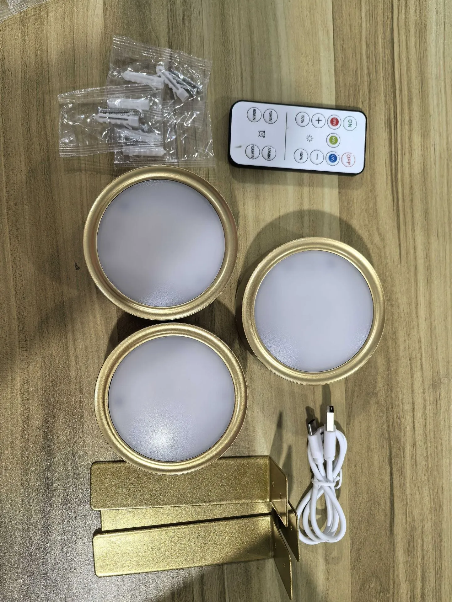 Magnetic LED light bars mounted around a painting, with a remote control on a table nearby.