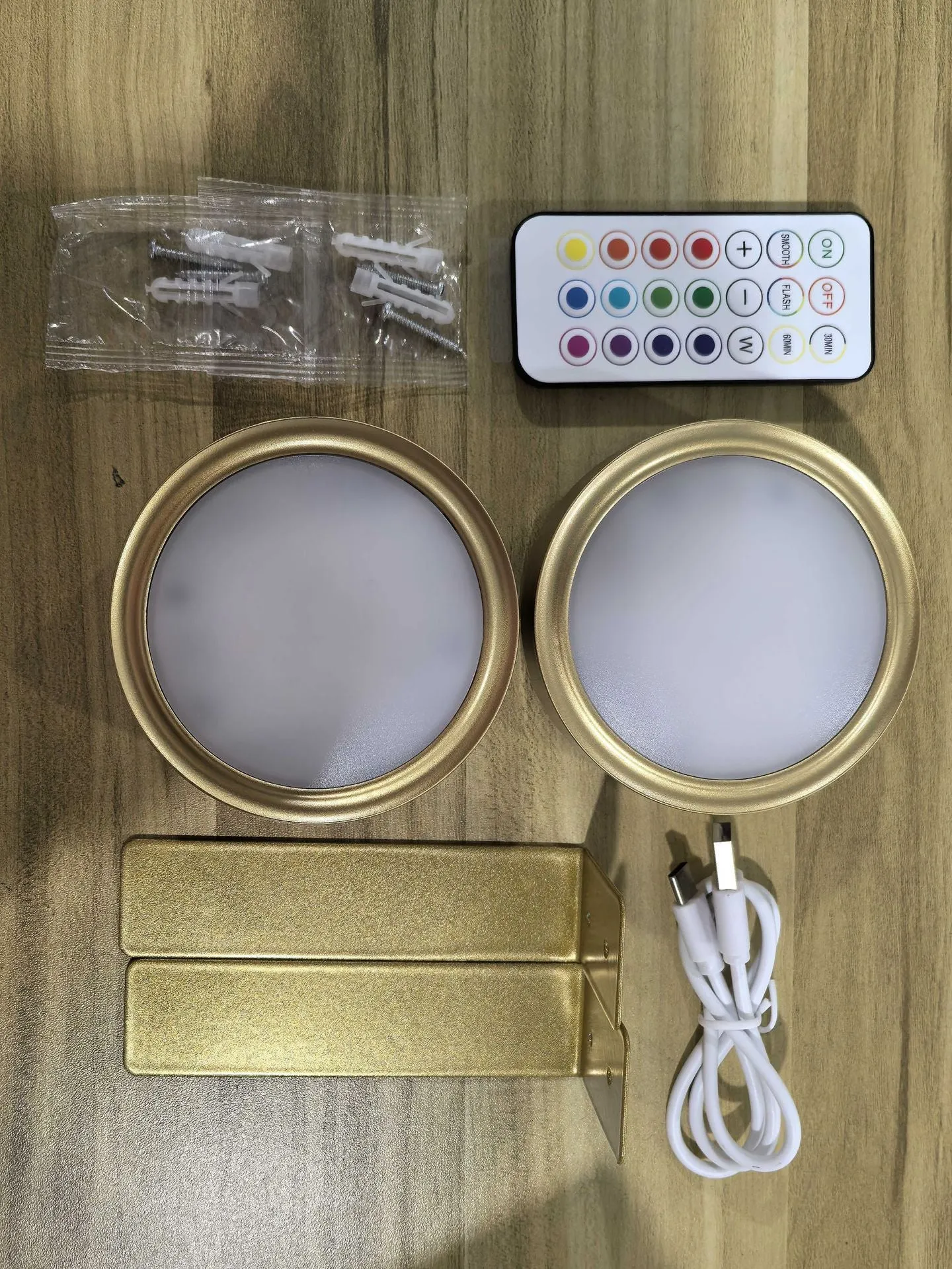 Magnetic LED light bars mounted around a painting, with a remote control on a table nearby.