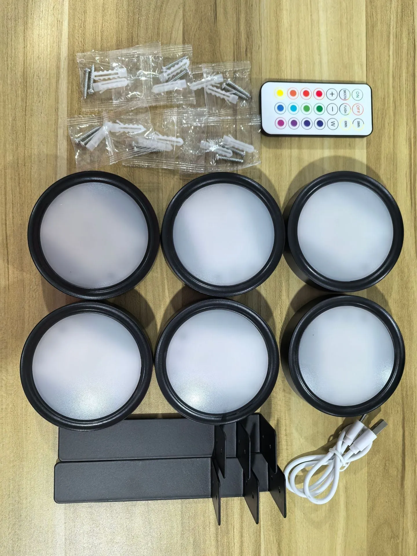 Magnetic LED light bars mounted around a painting, with a remote control on a table nearby.