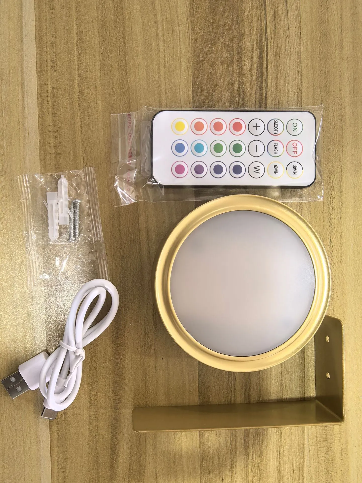 Magnetic LED light bars mounted around a painting, with a remote control on a table nearby.
