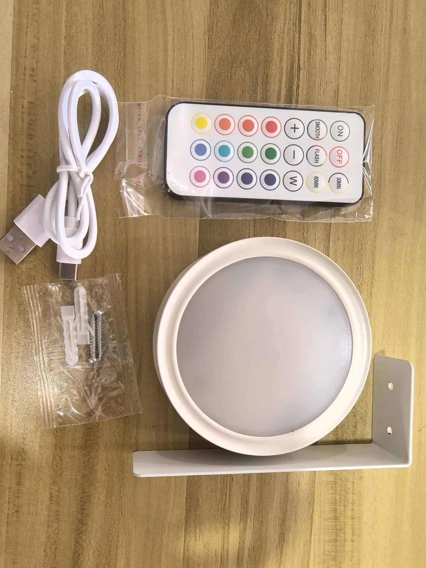 Magnetic LED light bars mounted around a painting, with a remote control on a table nearby.