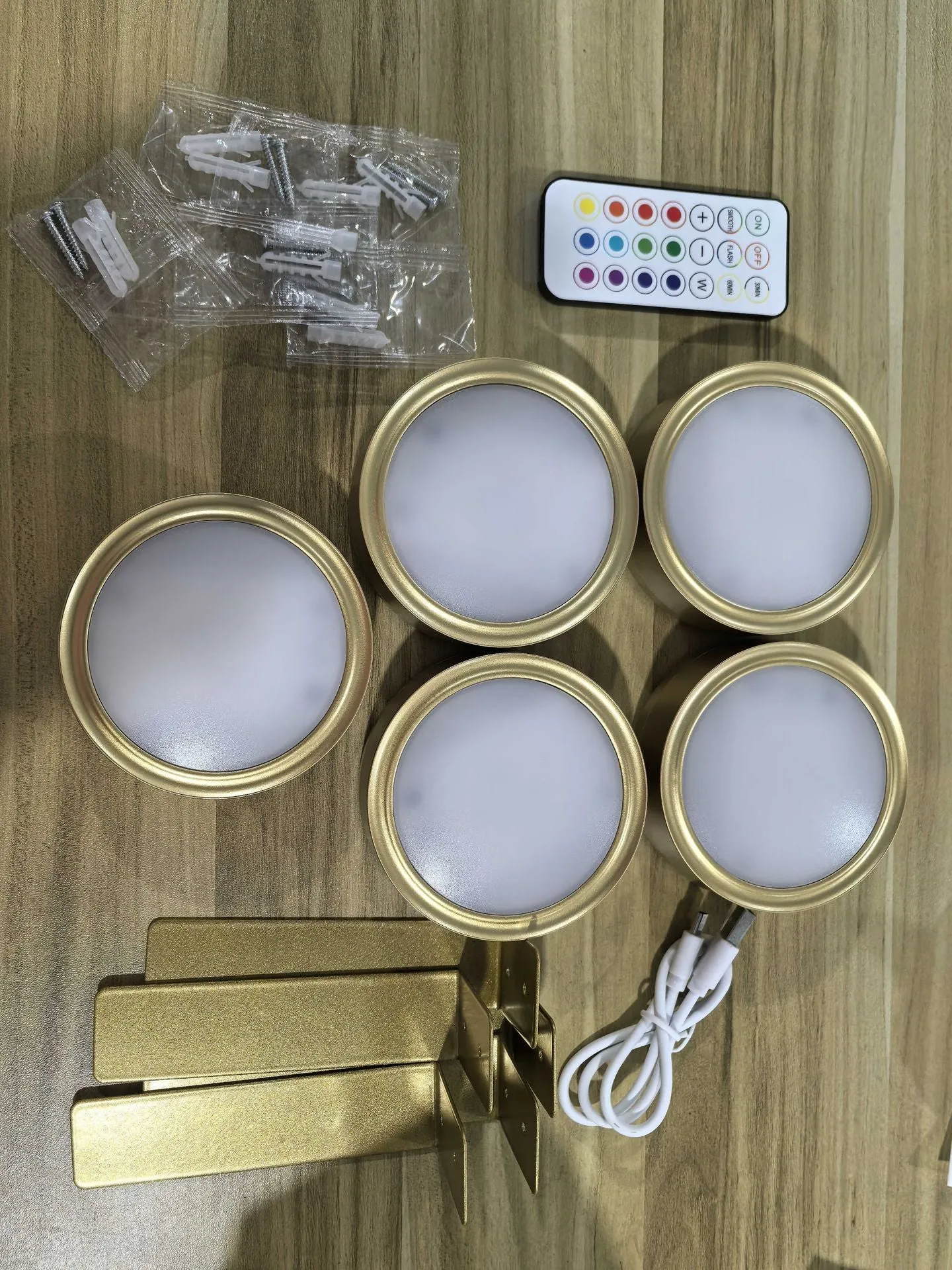 Magnetic LED light bars mounted around a painting, with a remote control on a table nearby.