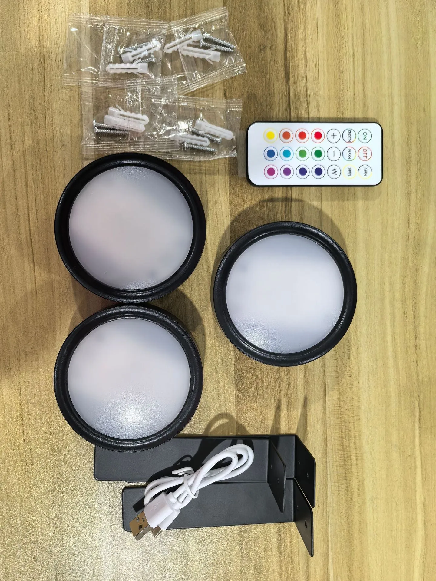 Magnetic LED light bars mounted around a painting, with a remote control on a table nearby.