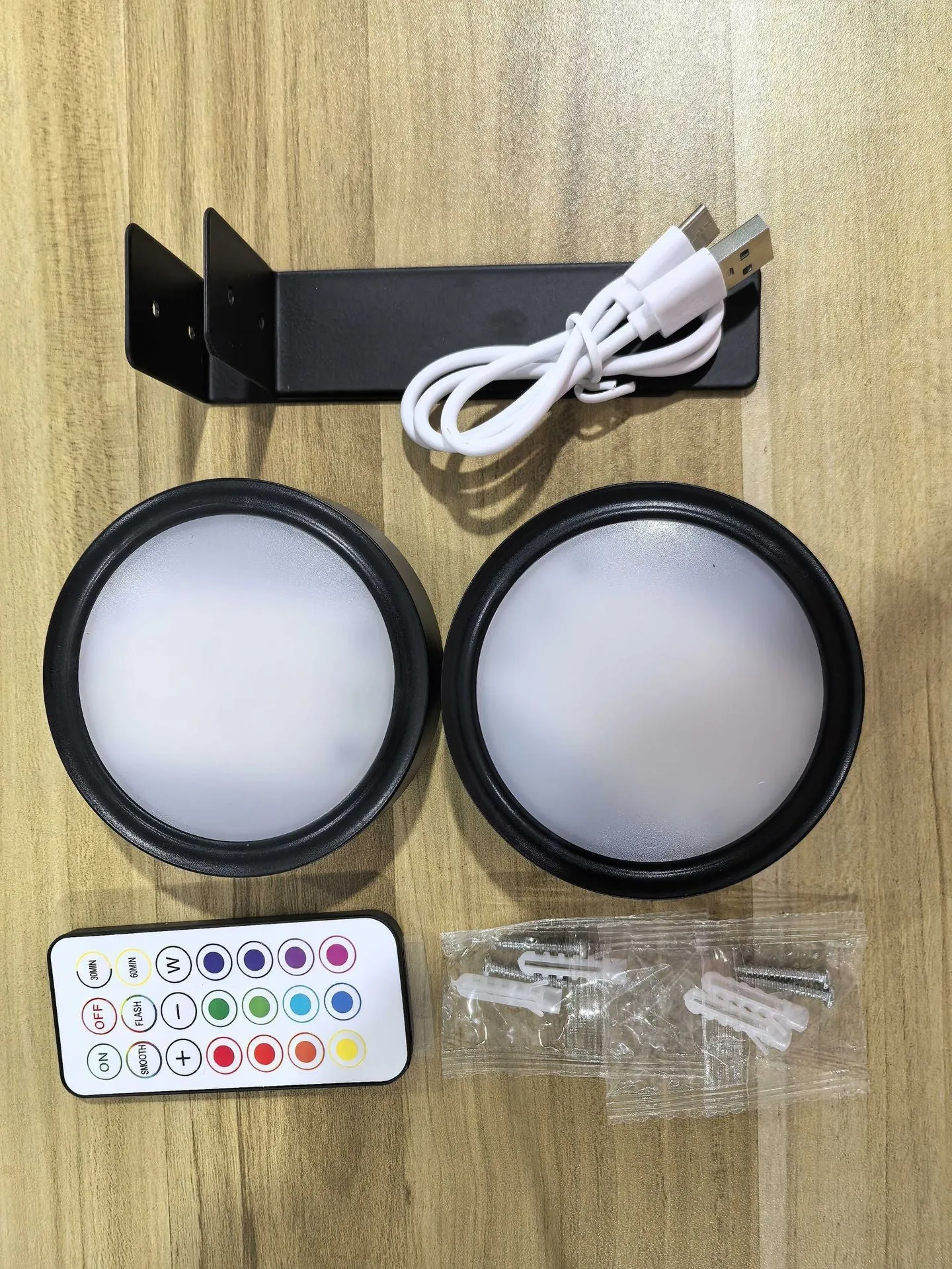 Magnetic LED light bars mounted around a painting, with a remote control on a table nearby.