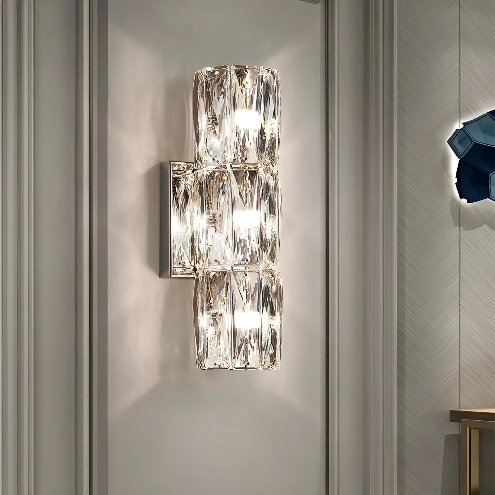 A sleek crystal wall lamp with a stainless steel base in chrome finish, mounted on a wall.