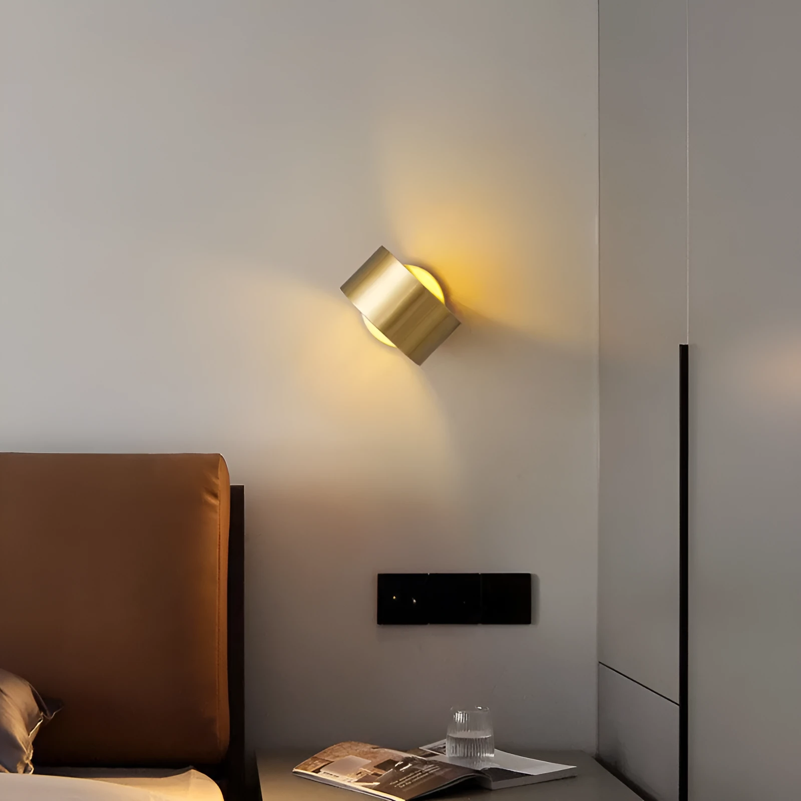 A modern simple style copper wall lamp in a gold finish, mounted on a wall.