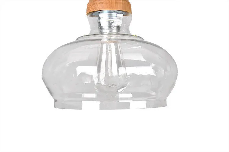 Single head glass pendant light with wood grain finish hanging from ceiling on adjustable cable.