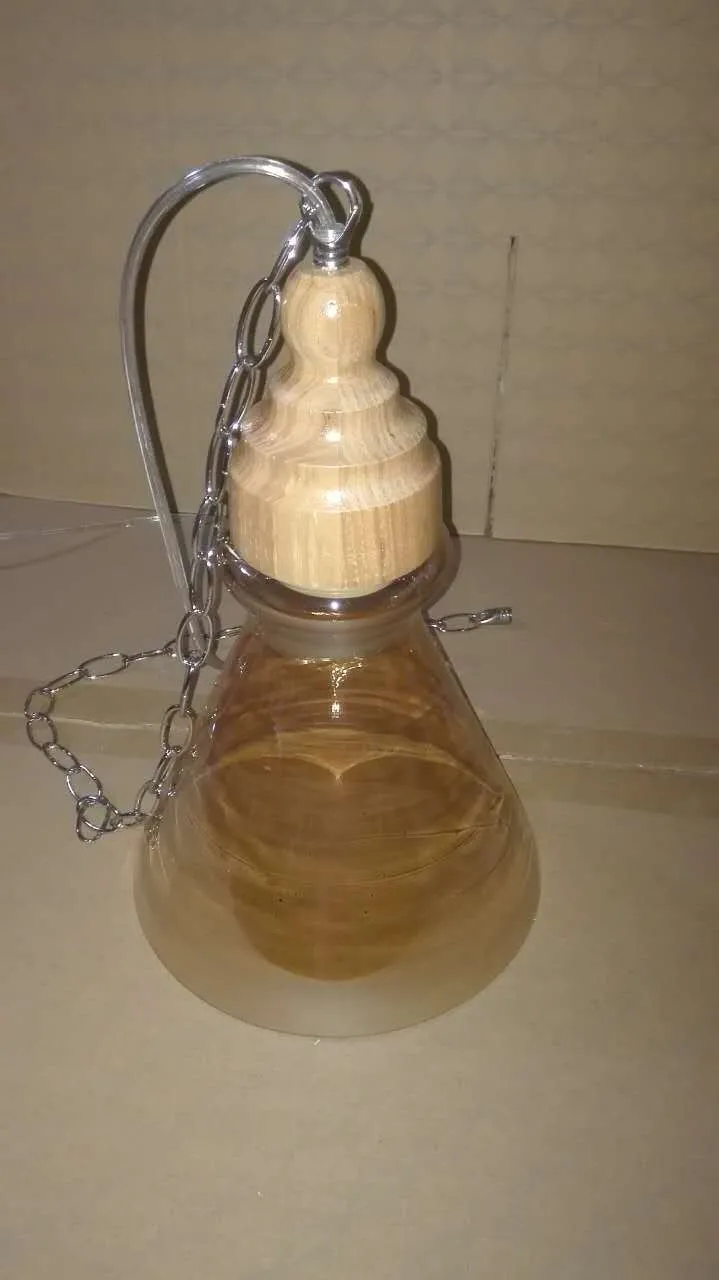 Single head glass pendant light with wood grain finish hanging from ceiling on adjustable cable.