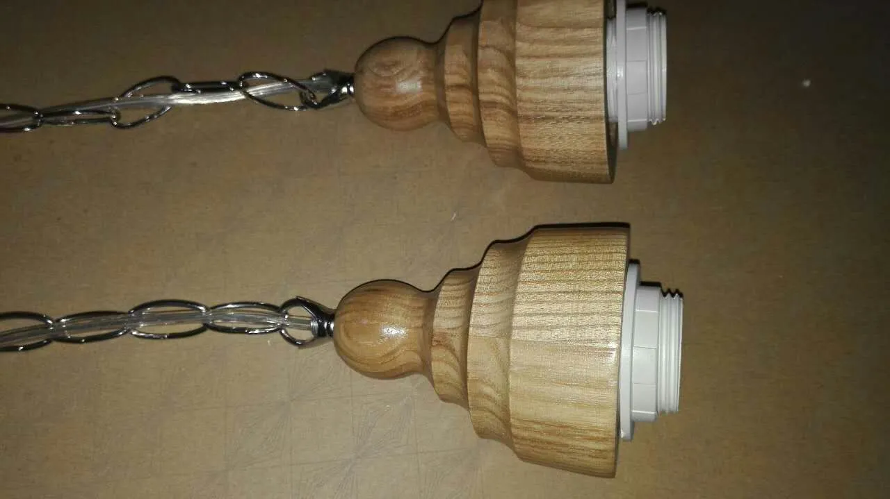 Single head glass pendant light with wood grain finish hanging from ceiling on adjustable cable.