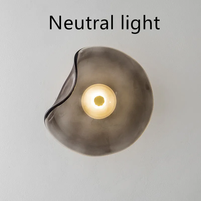 Round glass wall lamp for bedroom bedside in cognac, grey or light colour finishes.
