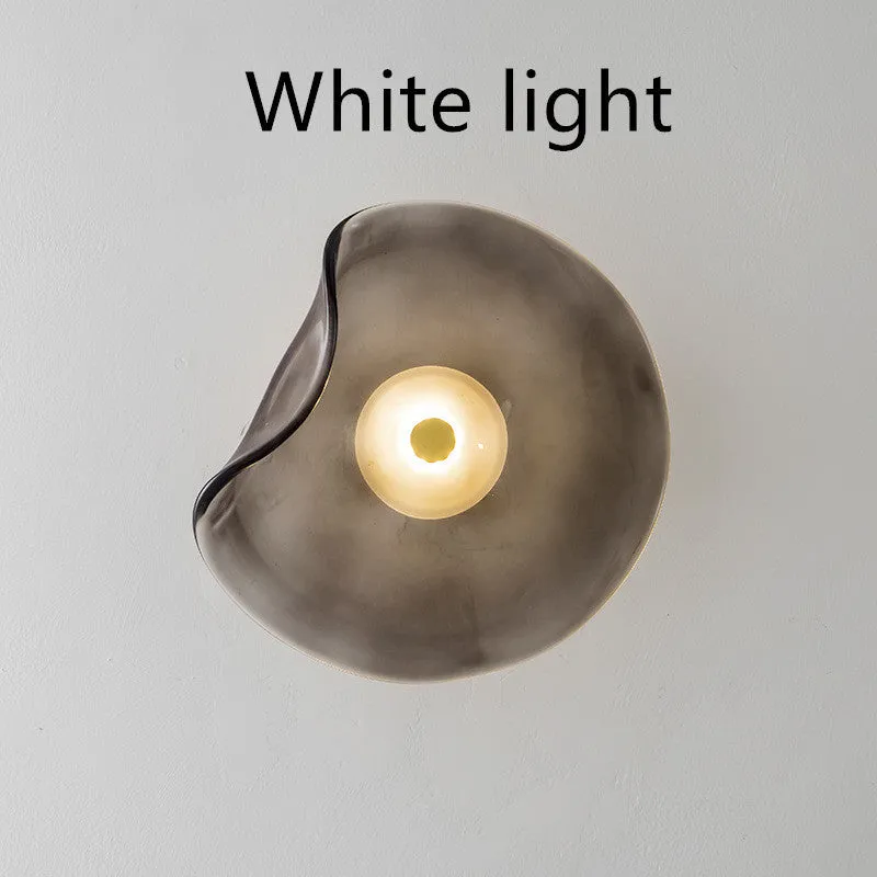 Round glass wall lamp for bedroom bedside in cognac, grey or light colour finishes.