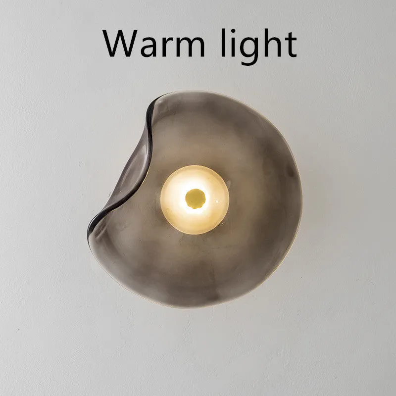 Round glass wall lamp for bedroom bedside in cognac, grey or light colour finishes.