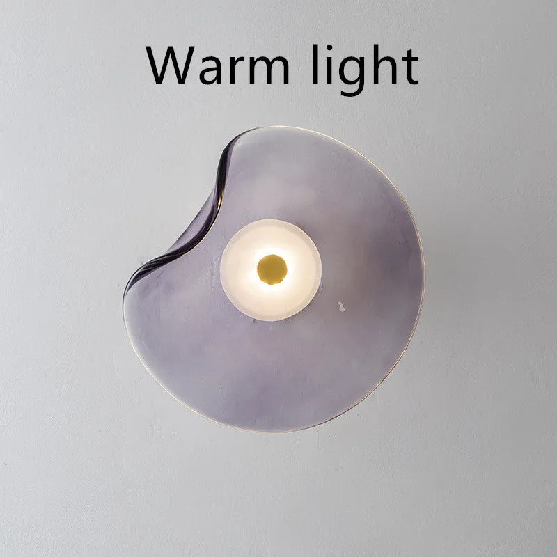 Round glass wall lamp for bedroom bedside in cognac, grey or light colour finishes.