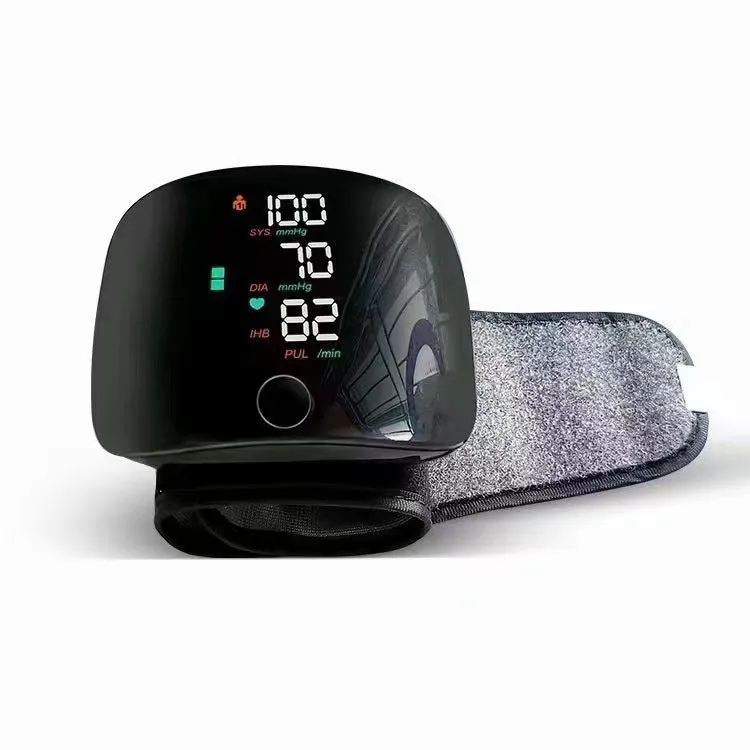 Black wrist blood pressure monitor with USB charging port on a table.