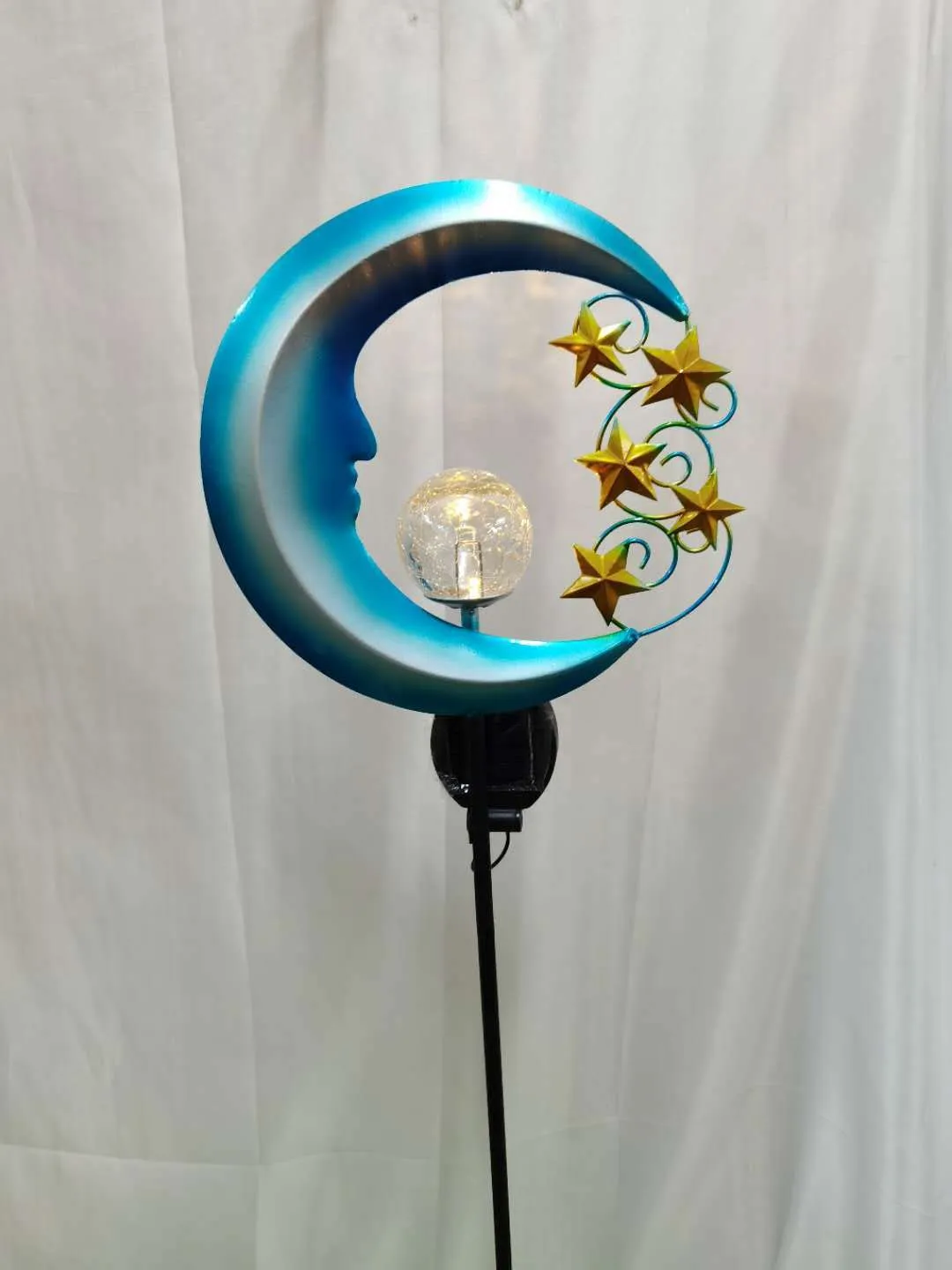 Blue moon and star design solar-powered wrought iron garden light with a glass ball.