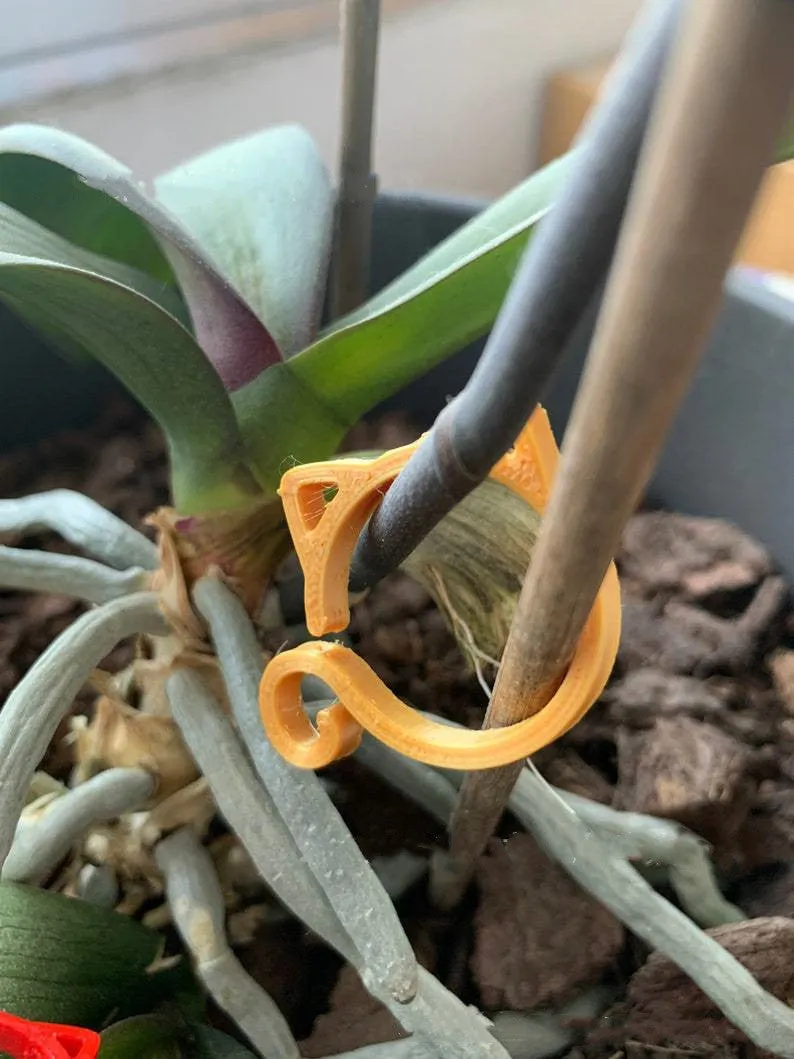Small green plastic plant clip shaped like a cat, shown next to a plant stem.