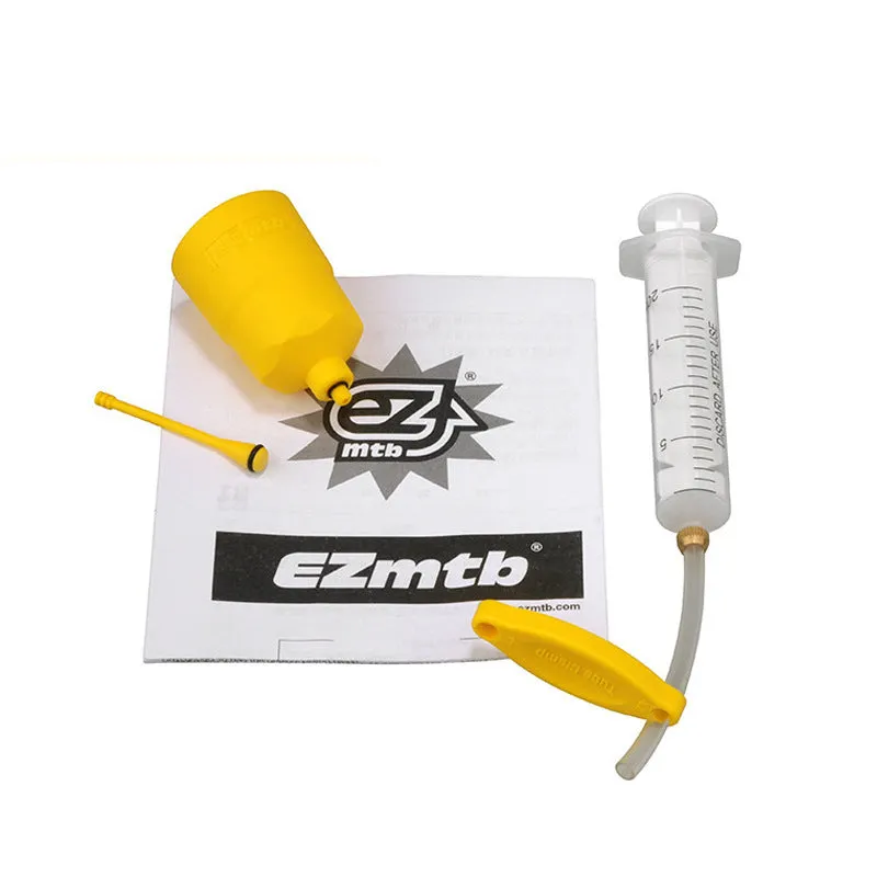 EZmtb bicycle hydraulic brake bleed kit with syringes, bottles, hoses, and metal adapters on a workbench.