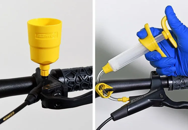 EZmtb bicycle hydraulic brake bleed kit with syringes, bottles, hoses, and metal adapters on a workbench.