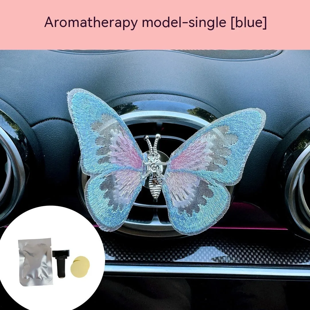 Soft fabric embroidered butterfly car air vent decoration in multiple colour options on a centre console.