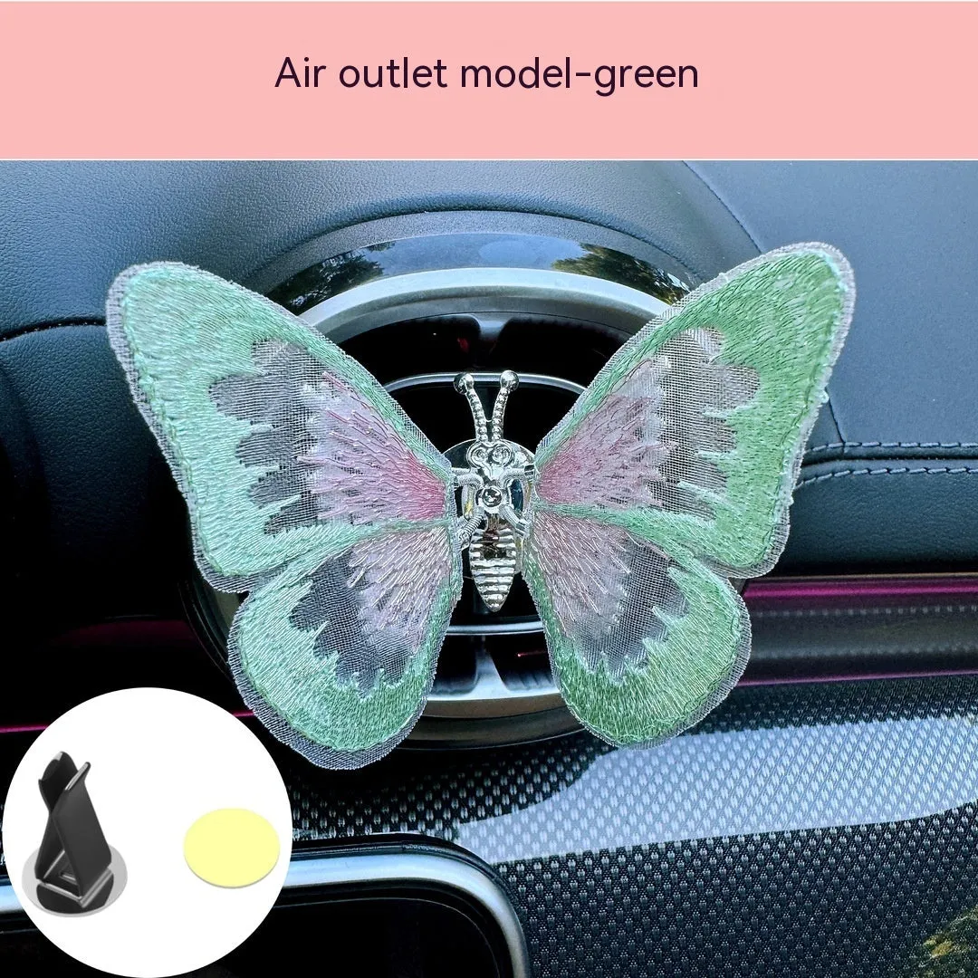 Soft fabric embroidered butterfly car air vent decoration in multiple colour options on a centre console.