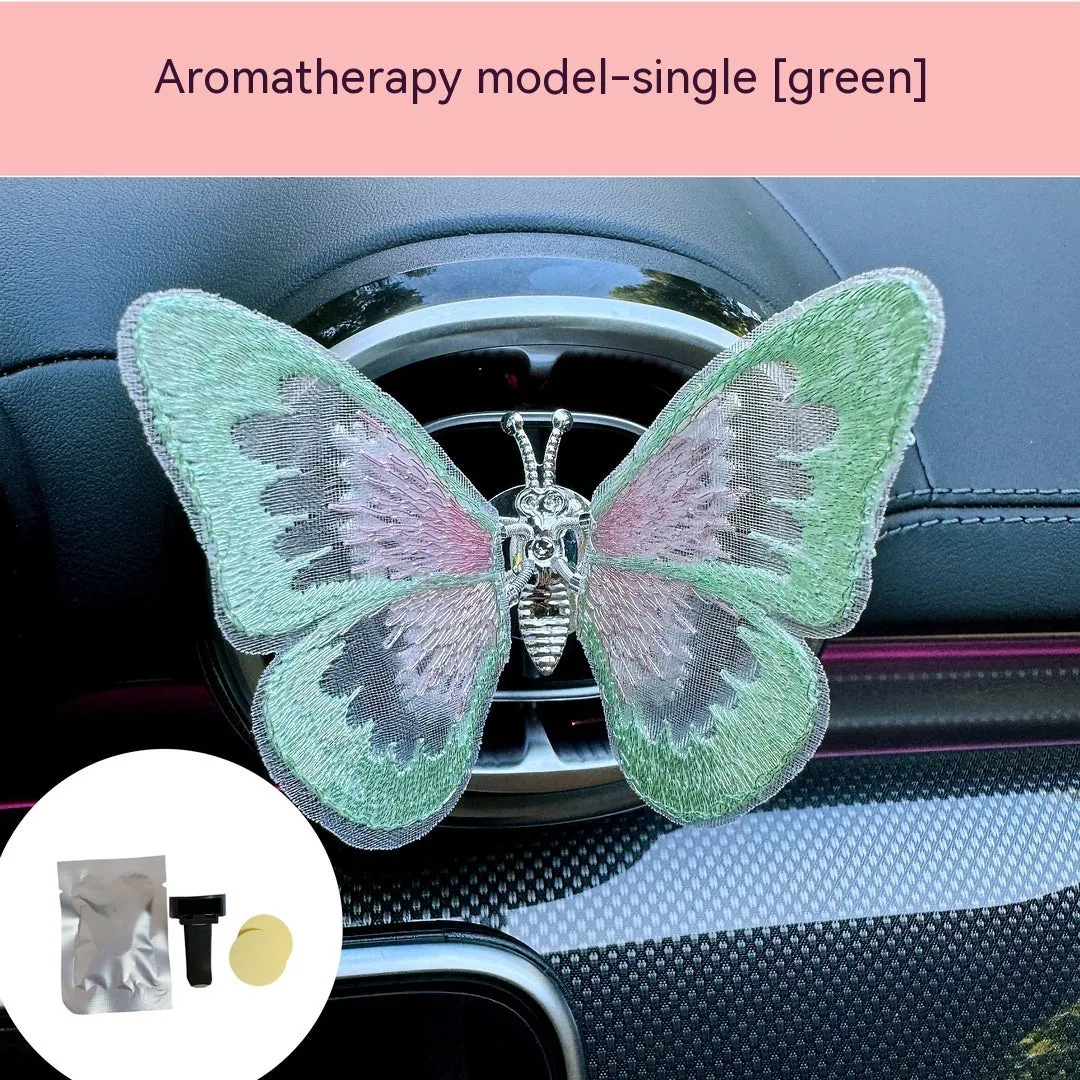 Soft fabric embroidered butterfly car air vent decoration in multiple colour options on a centre console.
