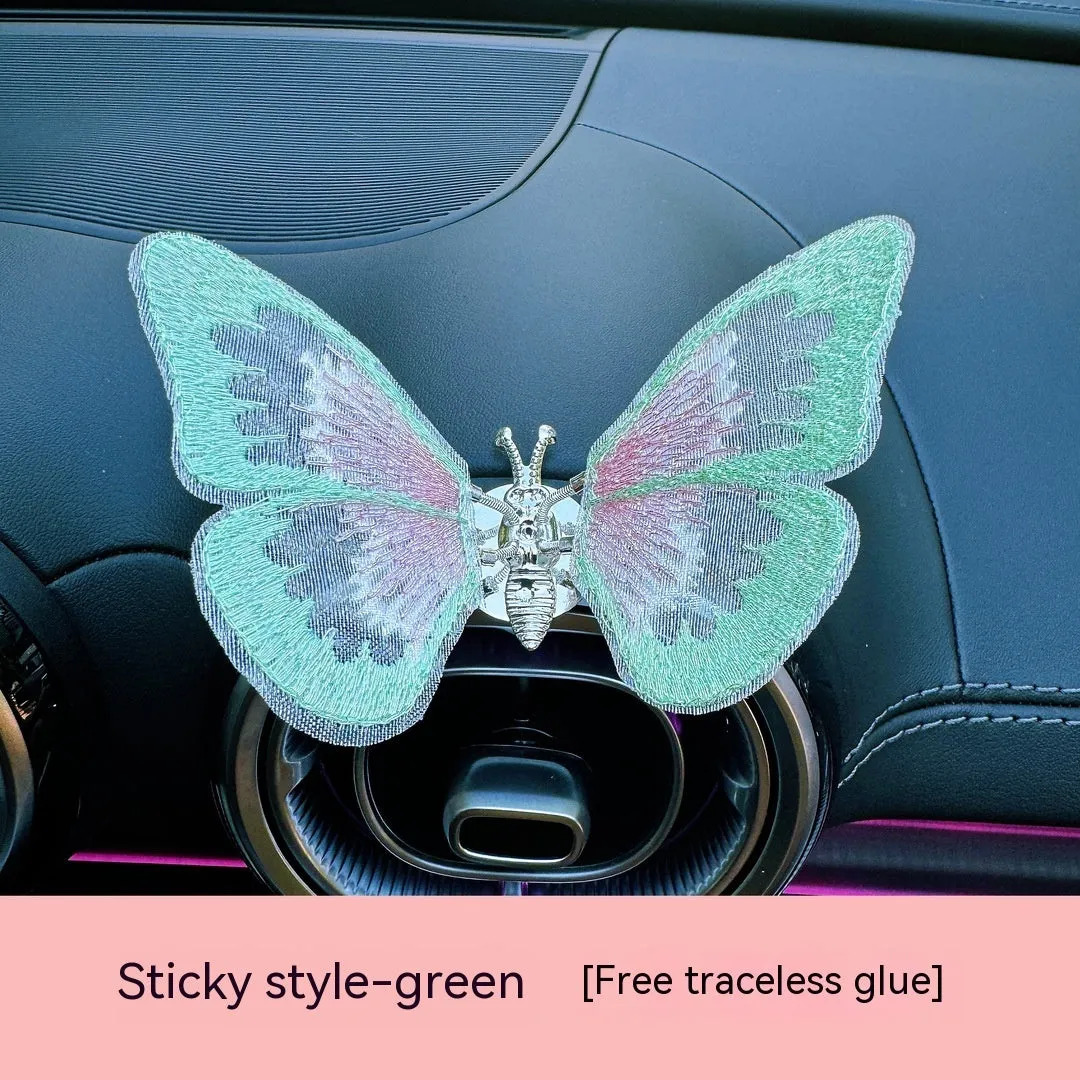Soft fabric embroidered butterfly car air vent decoration in multiple colour options on a centre console.