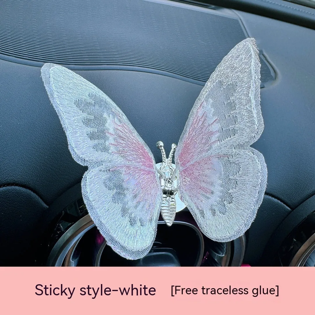 Soft fabric embroidered butterfly car air vent decoration in multiple colour options on a centre console.