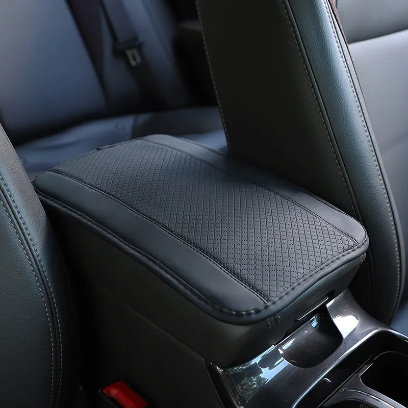 Embossed fibre leather car armrest box cushion measuring 32cm by 19cm in black with red trim
