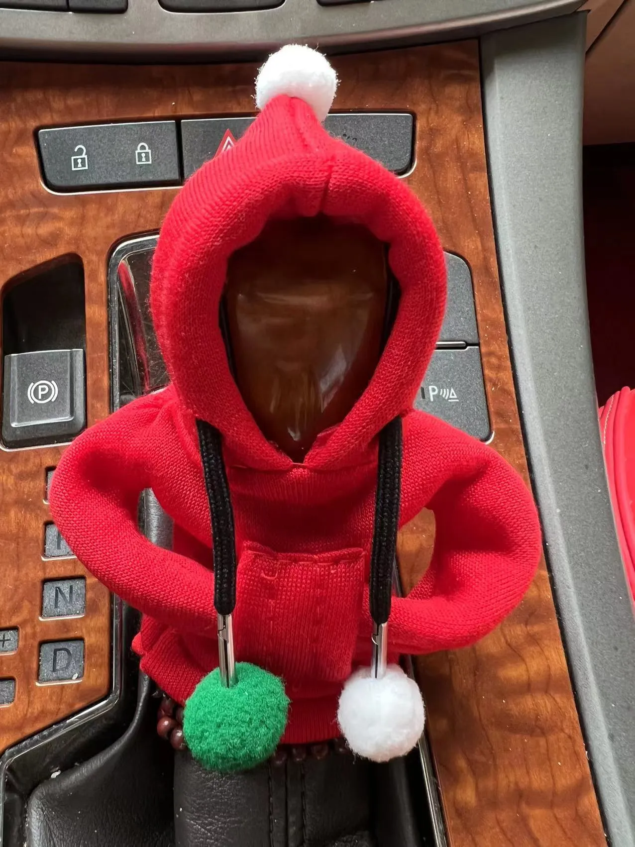 Red cloth hooded sweater cover on a car gear lever, showing decorative fur ball style.