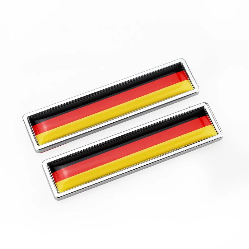 Pair of rectangular zinc alloy metal car badge stickers showing national flag designs, dimensions 58mm by 14mm.