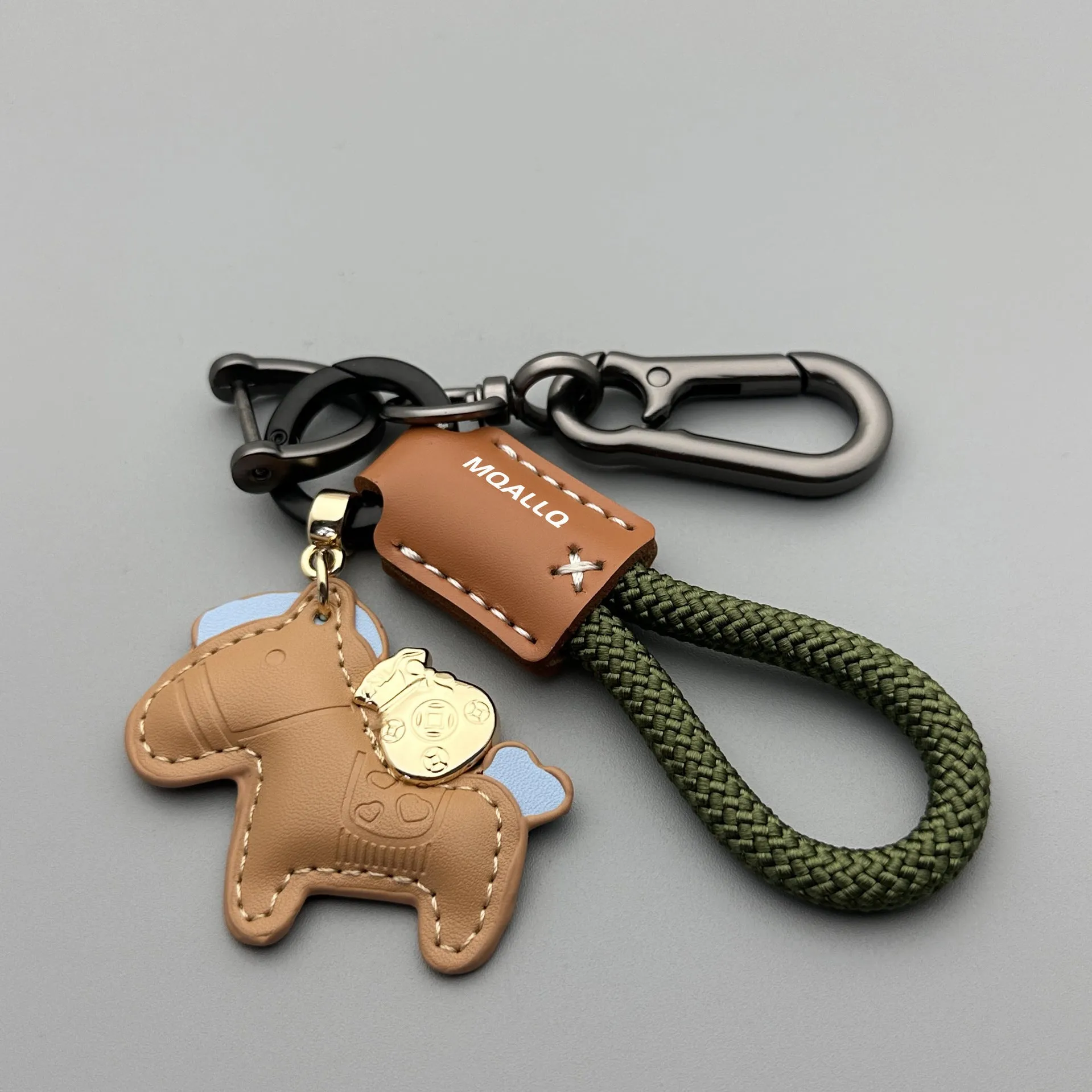 Handmade brown cowhide leather keychain with a zinc alloy pony belt buckle on a green flanelle rope.