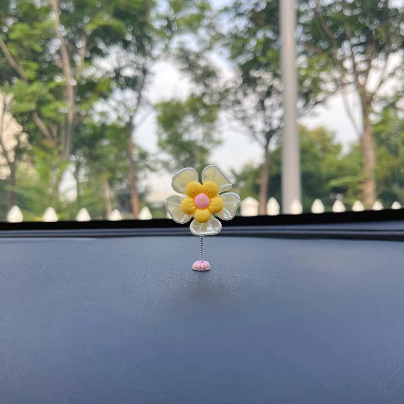 Small colourful plastic car decoration shaped like a swing, shown in multiple colour options.