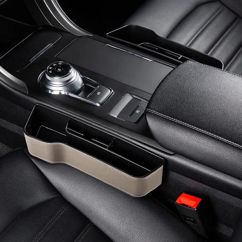 Black leather-style car seat gap storage box with cup holder and USB cable inserted between driver seat and centre console