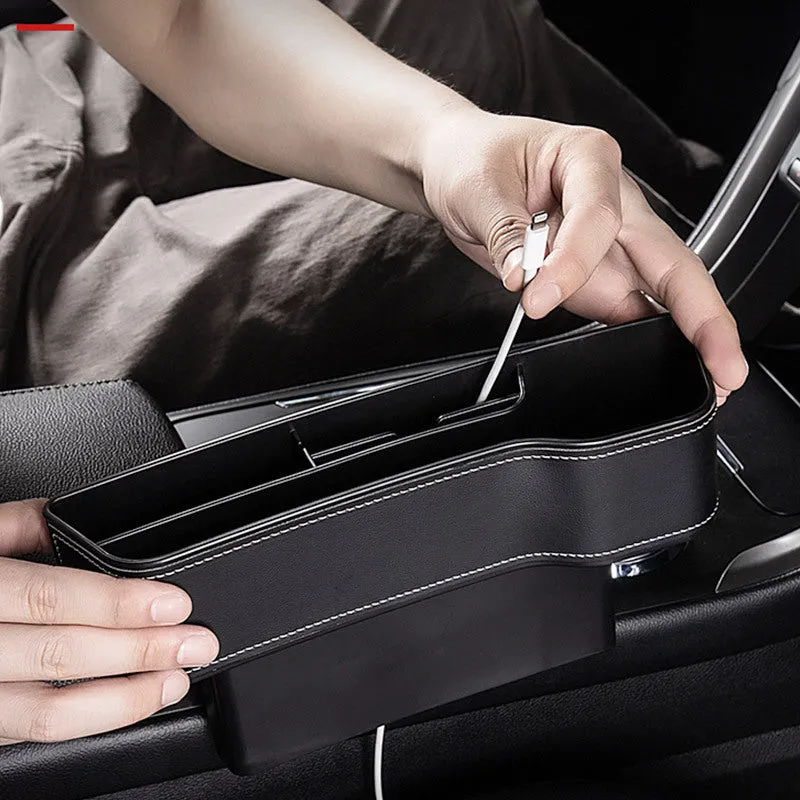 Black leather-style car seat gap storage box with cup holder and USB cable inserted between driver seat and centre console