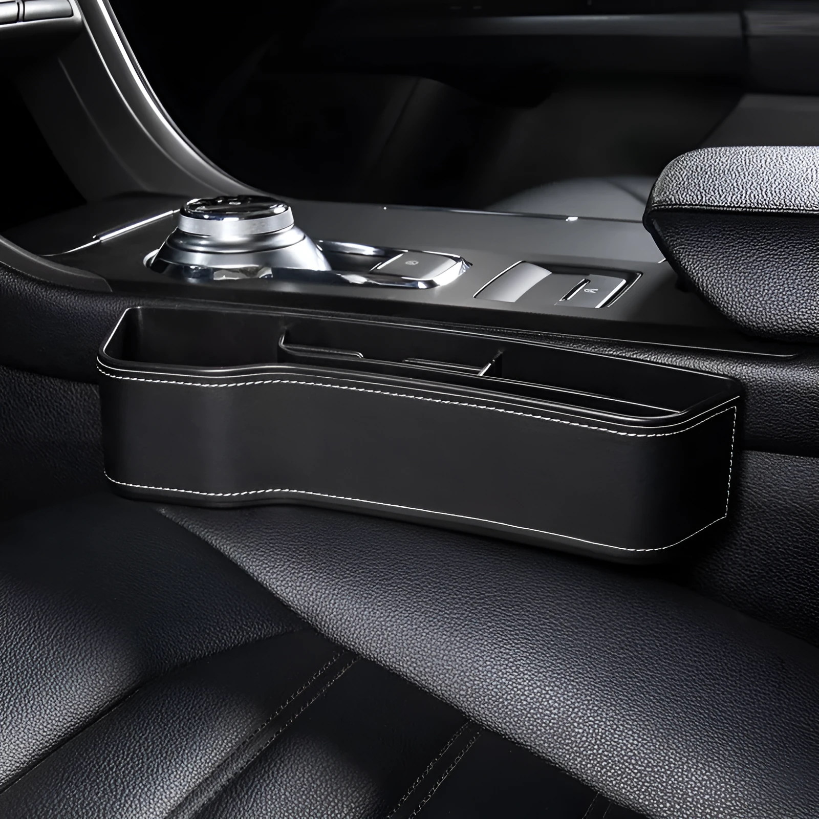 Black leather-style car seat gap storage box with cup holder and USB cable inserted between driver seat and centre console