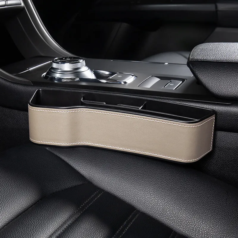 Black leather-style car seat gap storage box with cup holder and USB cable inserted between driver seat and centre console