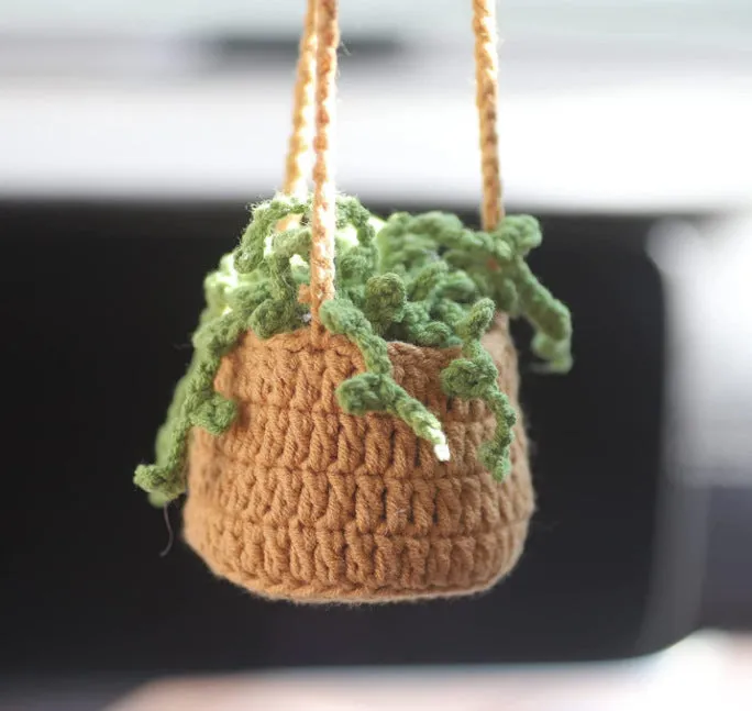 Green and white knitted wool car plant ornament with hanging rope.