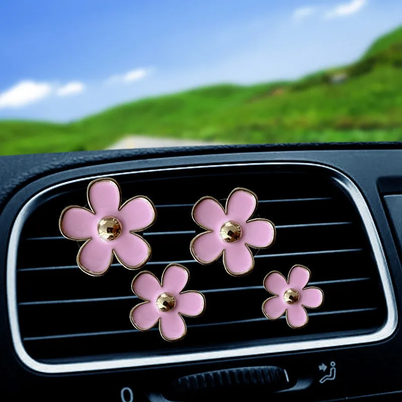 Set of four metal car air conditioning flower aromatherapy clips in assorted colours on white background