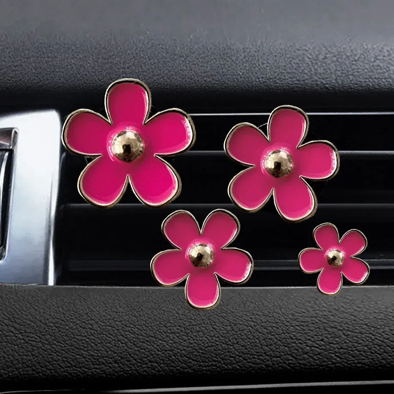 Set of four metal car air conditioning flower aromatherapy clips in assorted colours on white background
