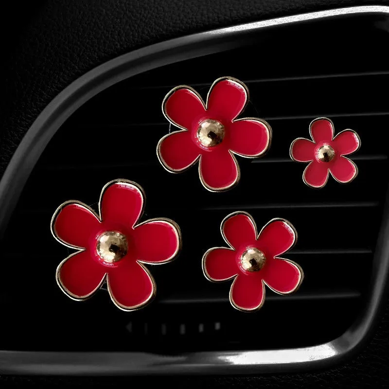 Set of four metal car air conditioning flower aromatherapy clips in assorted colours on white background