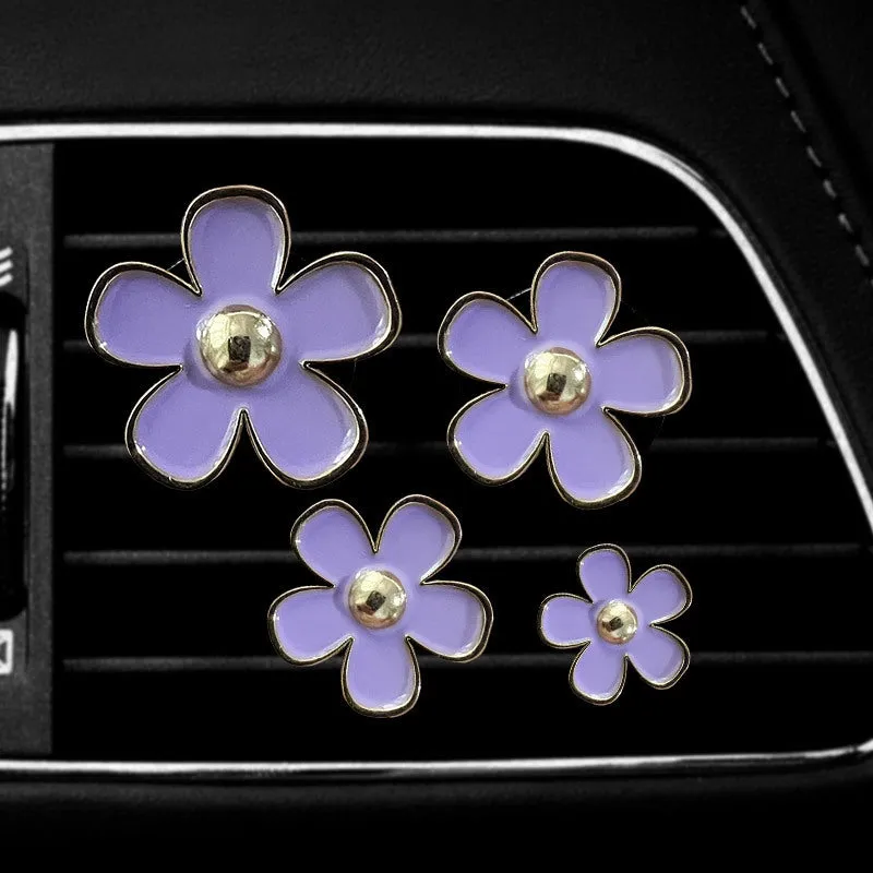 Set of four metal car air conditioning flower aromatherapy clips in assorted colours on white background