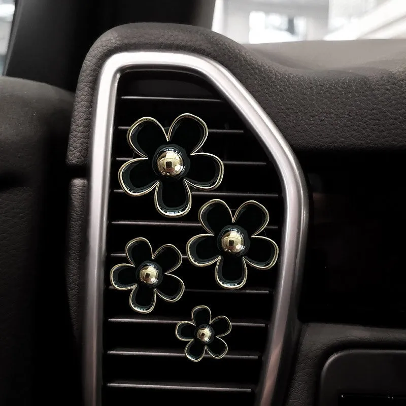 Set of four metal car air conditioning flower aromatherapy clips in assorted colours on white background