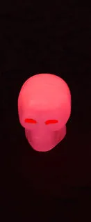 Luminous skull-shaped rubber car tyre valve cap in glow effect on a standard wheel