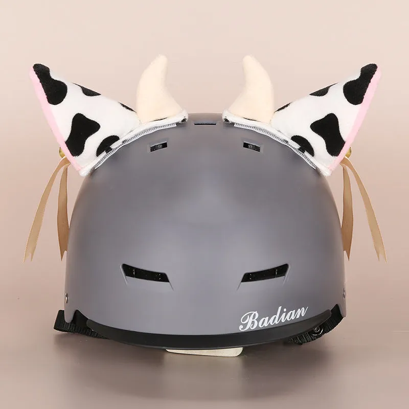 A soft plush cartoon character cover placed over a ski helmet on a snowy background.