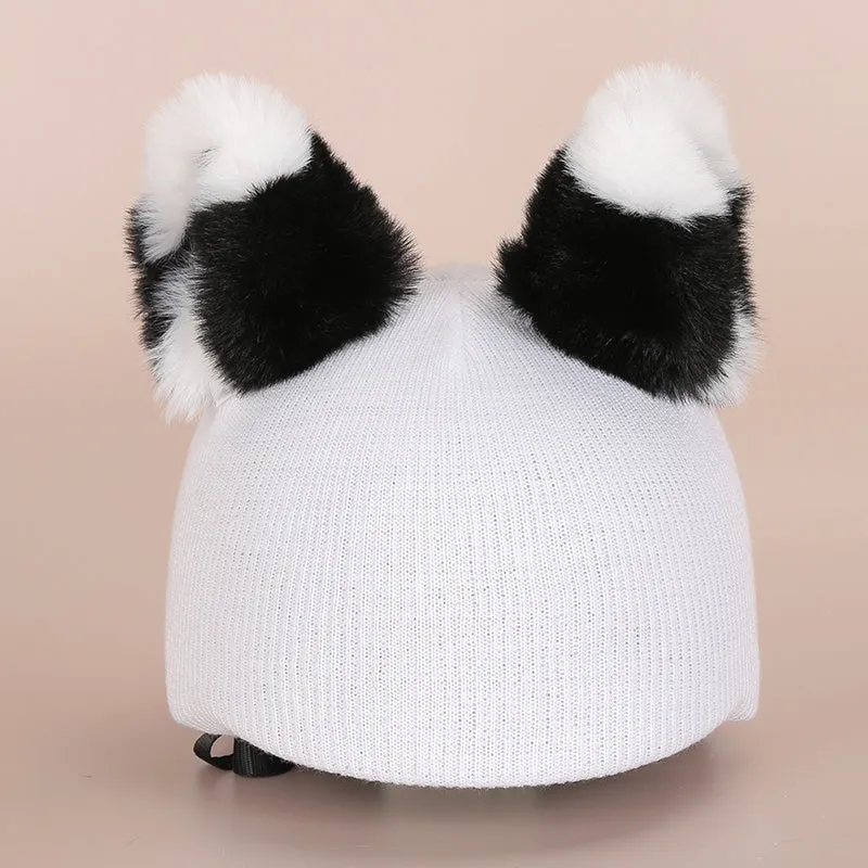 A soft plush cartoon character cover placed over a ski helmet on a snowy background.