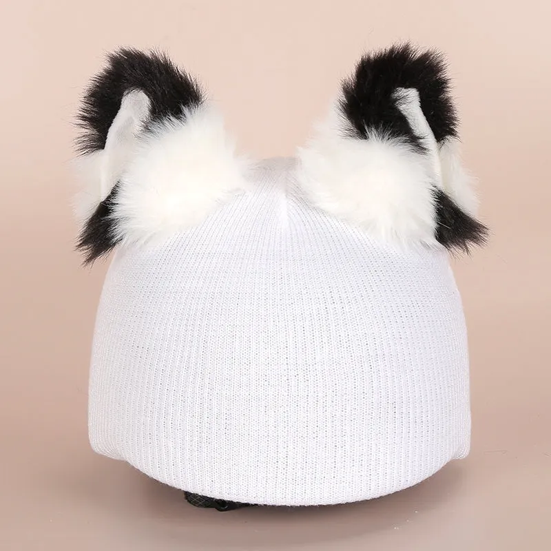 A soft plush cartoon character cover placed over a ski helmet on a snowy background.