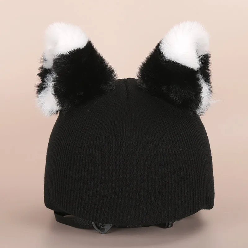 A soft plush cartoon character cover placed over a ski helmet on a snowy background.