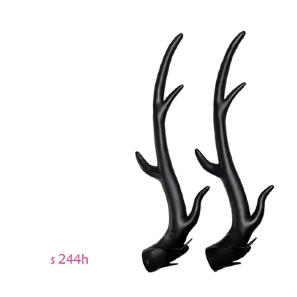 Pair of black resin dragon horn decorations next to a motorcycle helmet, showing scale and detailed texture.