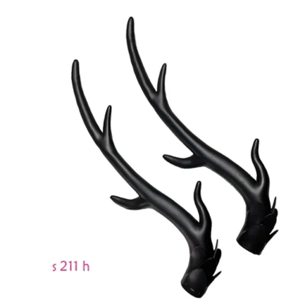 Pair of black resin dragon horn decorations next to a motorcycle helmet, showing scale and detailed texture.