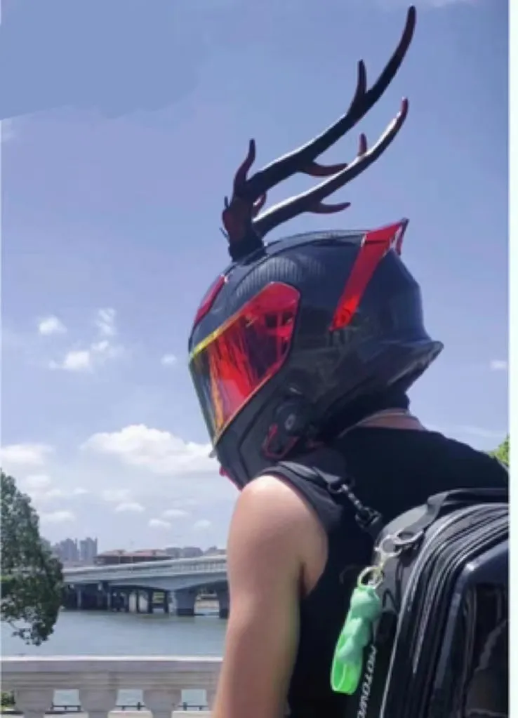 Pair of black resin dragon horn decorations next to a motorcycle helmet, showing scale and detailed texture.